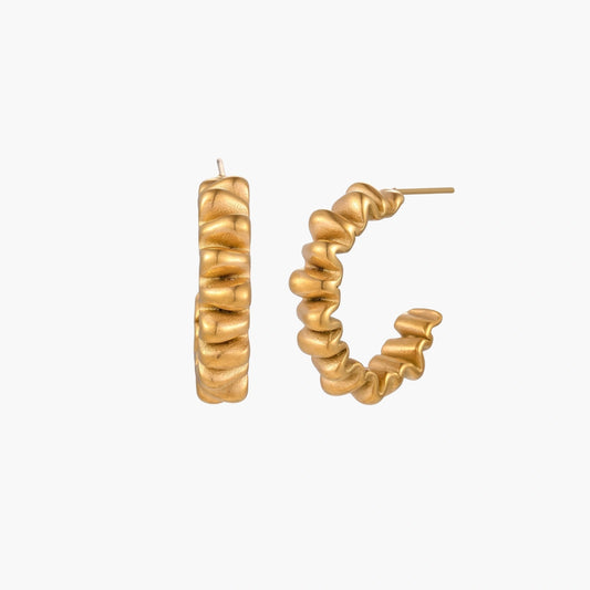 Sculptural gold-plated hoop earrings with continuous twisted spiral design on cream background